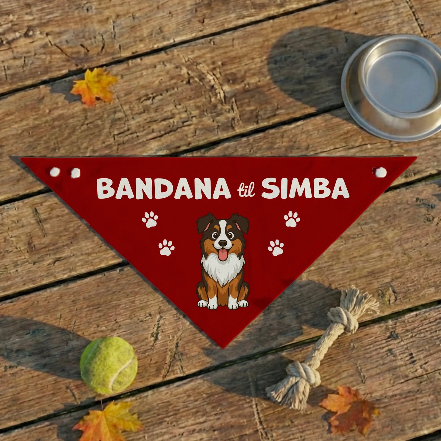 Rød personlig bandana til hund med navnet 'Simba' og tegning af en glad hund, liggende på trægulv med legetøj.