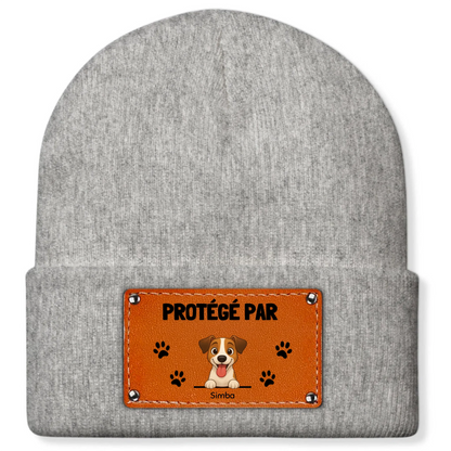 Dettaglio della patch marrone cucita con stampa 'PROTETTO DA', zampette nere e un cane stilizzato.