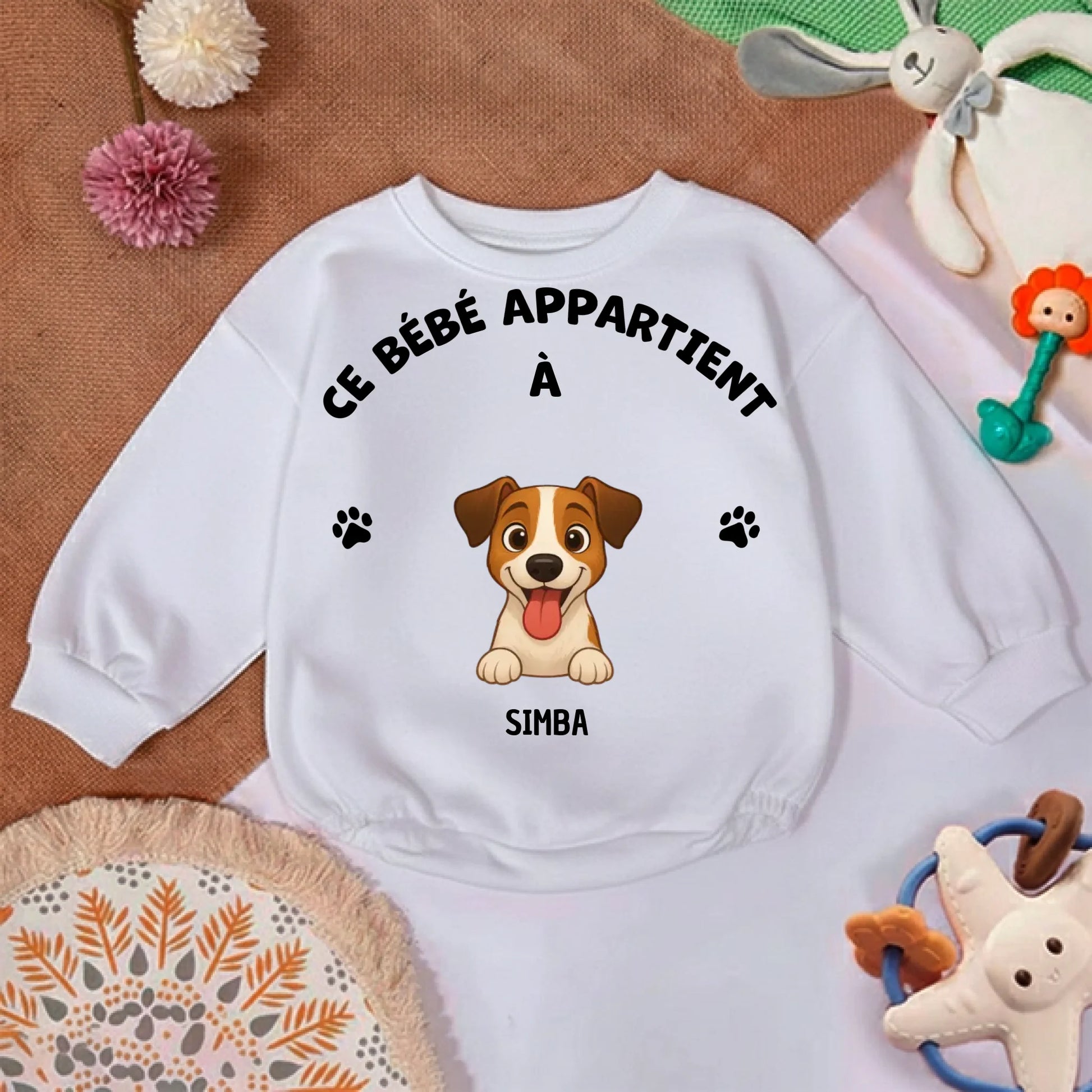 Zoom sur le motif du pull bébé: illustration détaillée d'un chien joyeux avec ses pattes et le prénom "SIMBA".