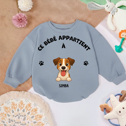 Pull bébé personnalisé posé sur un tapis doux, entouré de jouets, suggérant un usage confortable et ludique à la maison.