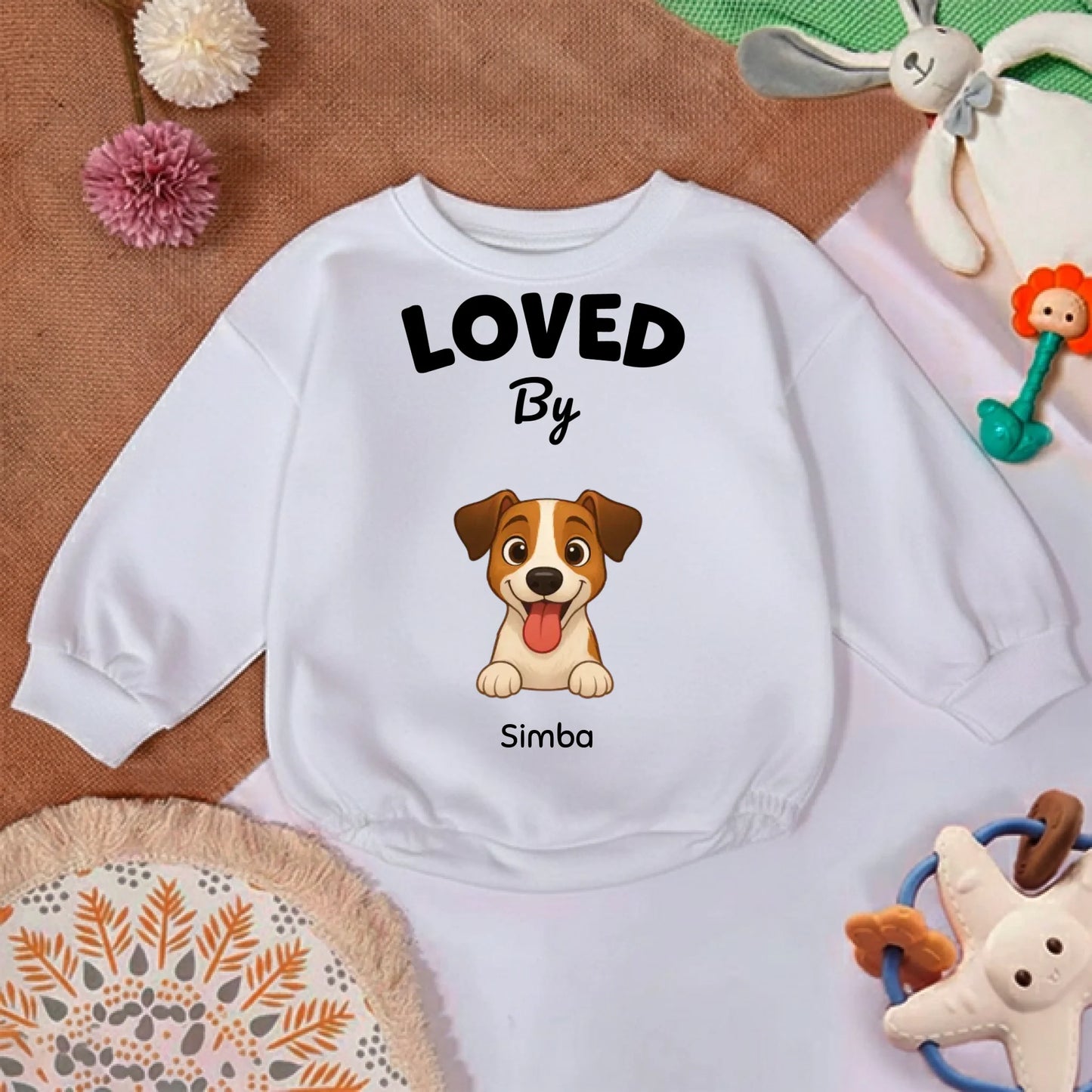 Détail du col et du texte "LOVED By" sur le pull bébé camel doux et confortable.