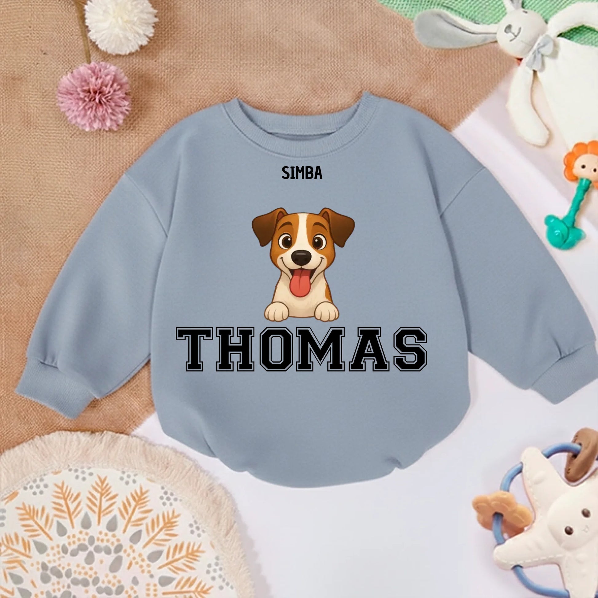 Pull bébé personnalisé posé sur tapis doux avec jouets, ambiance chaleureuse et joyeuse.
