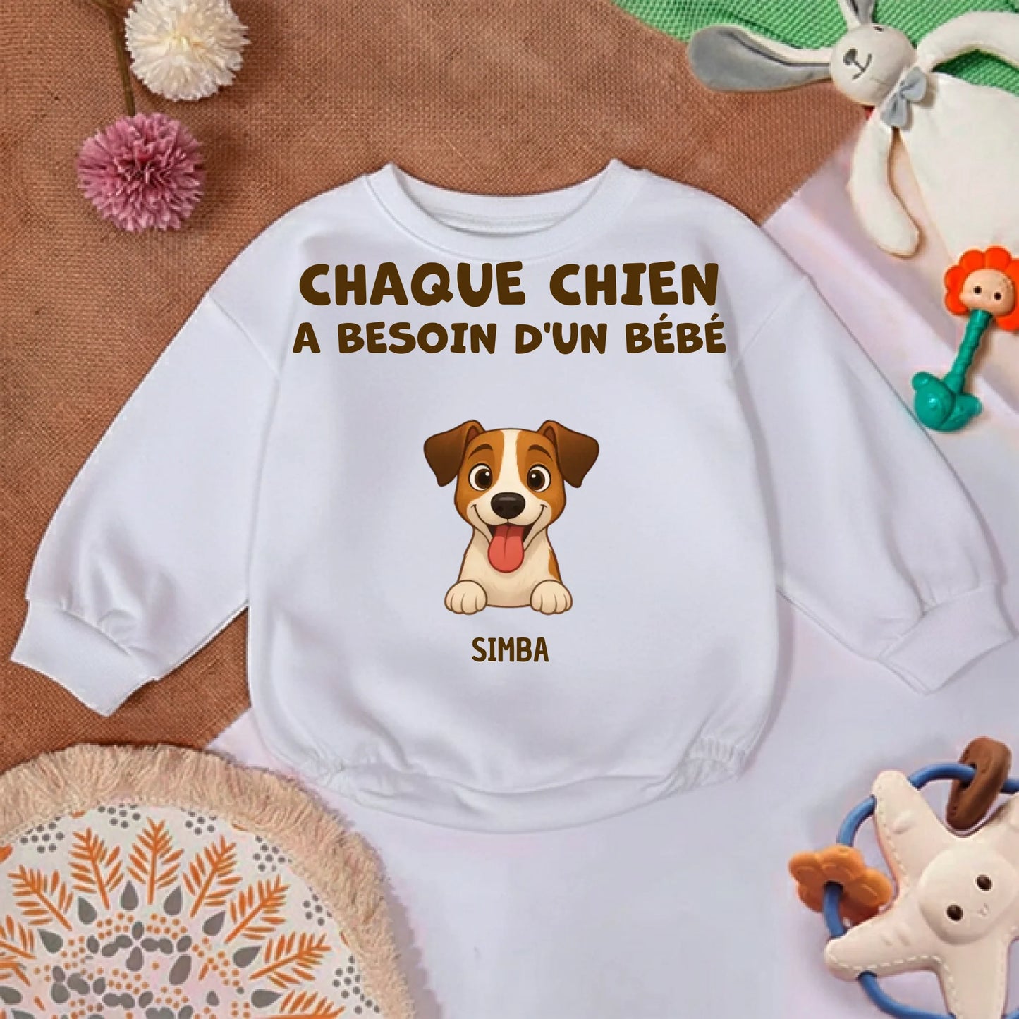 Gros plan sur le motif du pull bébé: illustration d'un chien souriant et le prénom Simba.
