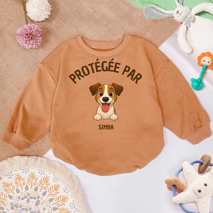 Pull bébé personnalisé couleur camel avec illustration d'un chien Jack Russell souriant et le texte 'Protégée par Simba'.