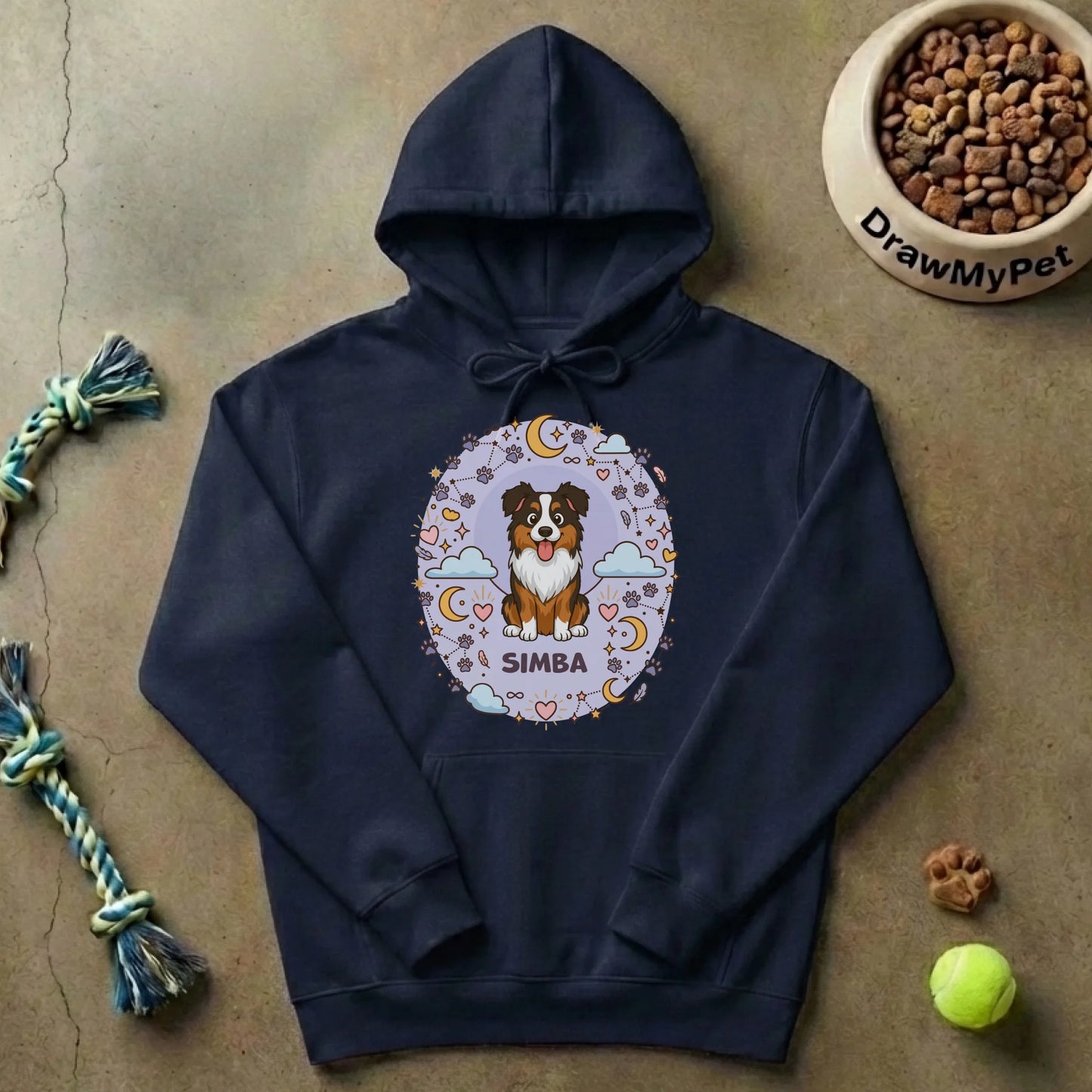 Pull à capuche personnalisé posé sur sol, entouré de jouets et gamelle pour chien, ambiance cocooning.