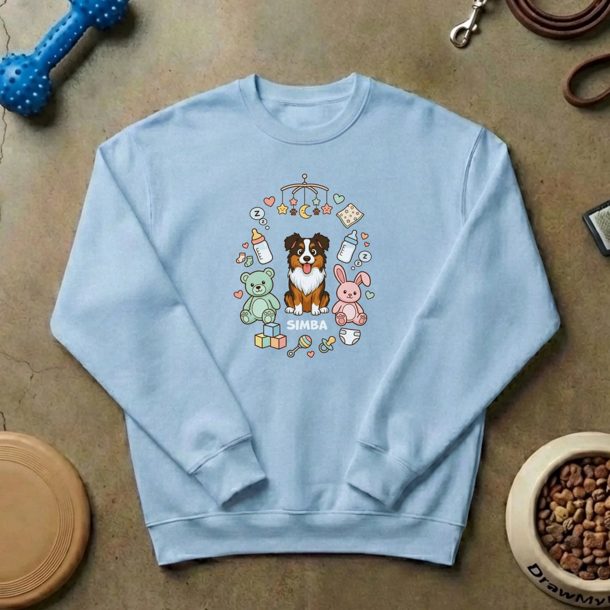 Suéter blanco personalizado 'La familia crece' con un diseño de perro y bebé, junto a un juguete y cuenco de comida para mascotas