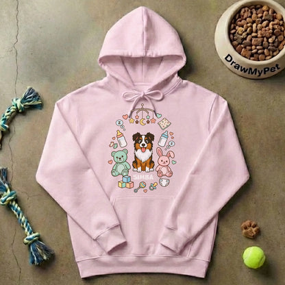 Primer plano del diseño de un perro rodeado de elementos de bebé en la sudadera "La familia crece".