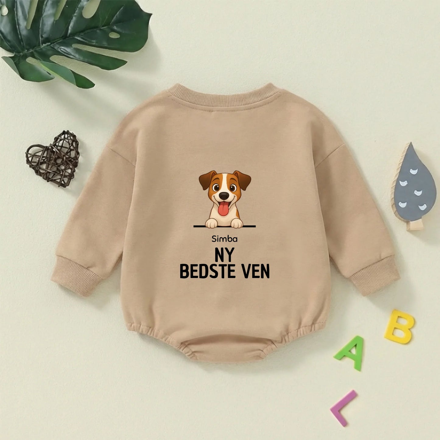 Nærbillede af den glade tegning af hunden og teksten 'NY BEDSTE VEN' på den grønne babybody.
