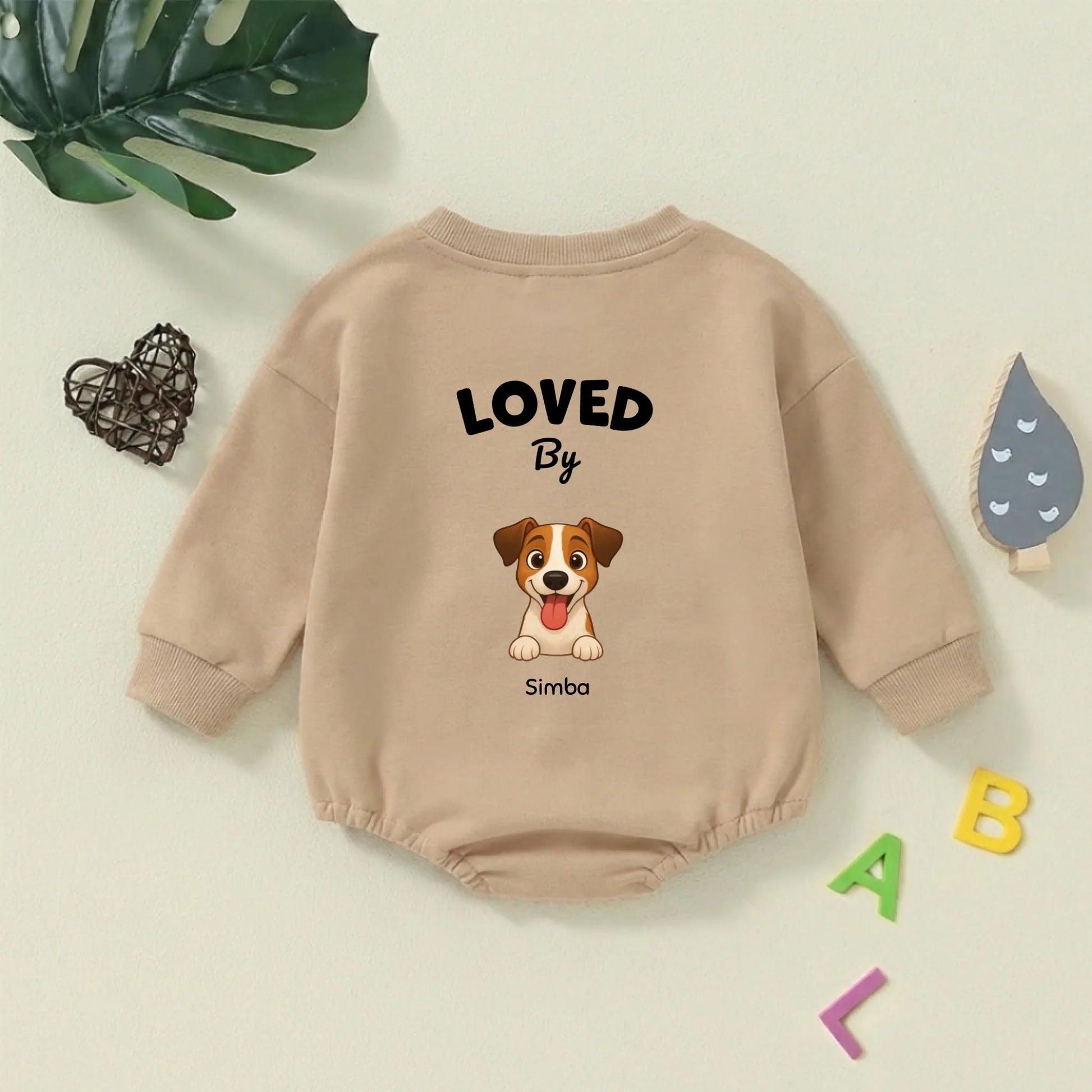 Primo piano del dolce ritratto di cane stilizzato e della scritta 'Loved by' sul body per neonato