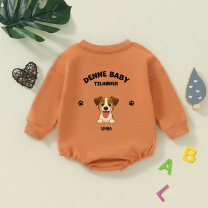 Mørkegrøn babybody med personligt hundemotiv liggende fladt med dekorative bogstaver og naturpynt i baggrunden, klar til babyens brug.