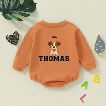 Body infantil verde con ilustración de perrito y nombres, colocado sobre un fondo claro con una hoja de monstera, un corazón de mimbre y letras de juguete, sugiriendo un ambiente de guardería.