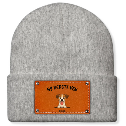 Detalje: Brunt hue-patch med tegnet hund, slogan 'NY BEDSTE VEN' og navn.