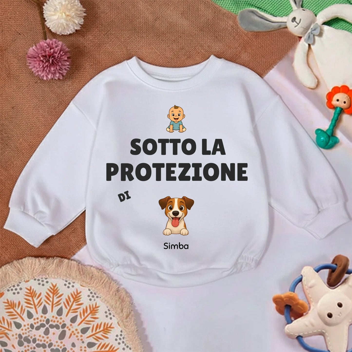 Dettaglio della stampa 'Sotto la protezione di' con icona di bebè e ritratto di cane sul maglioncino.