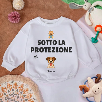Dettaglio della stampa 'Sotto la protezione di' con icona di bebè e ritratto di cane sul maglioncino.