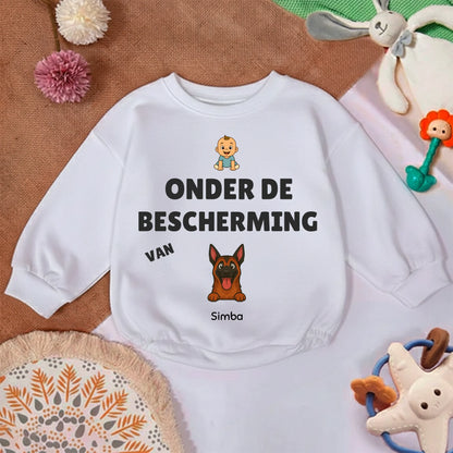 Close-up van de zachte stof en de opdruk 'Onder de bescherming van' op de babytrui.