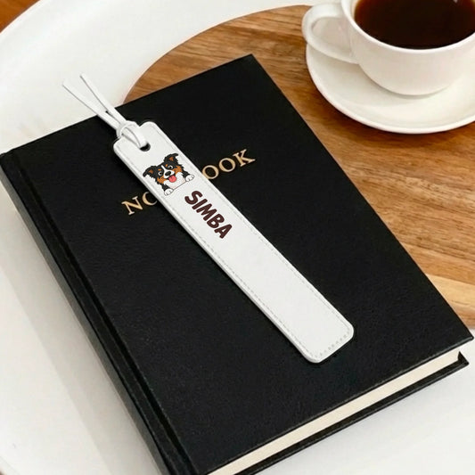 Personalized leather bookmark for dog Simba with cartoon portrait, tucked into a black book.