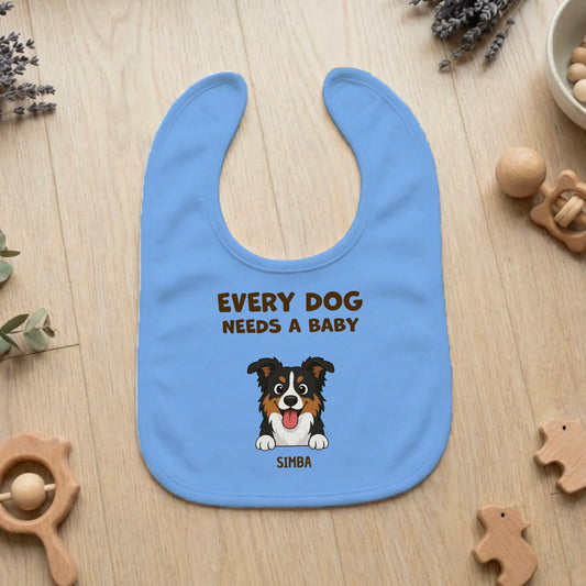 Personalized light blue baby bib with "Every Dog Needs a Baby" slogan and a happy cartoon Australian Shepherd portrait named Simba.